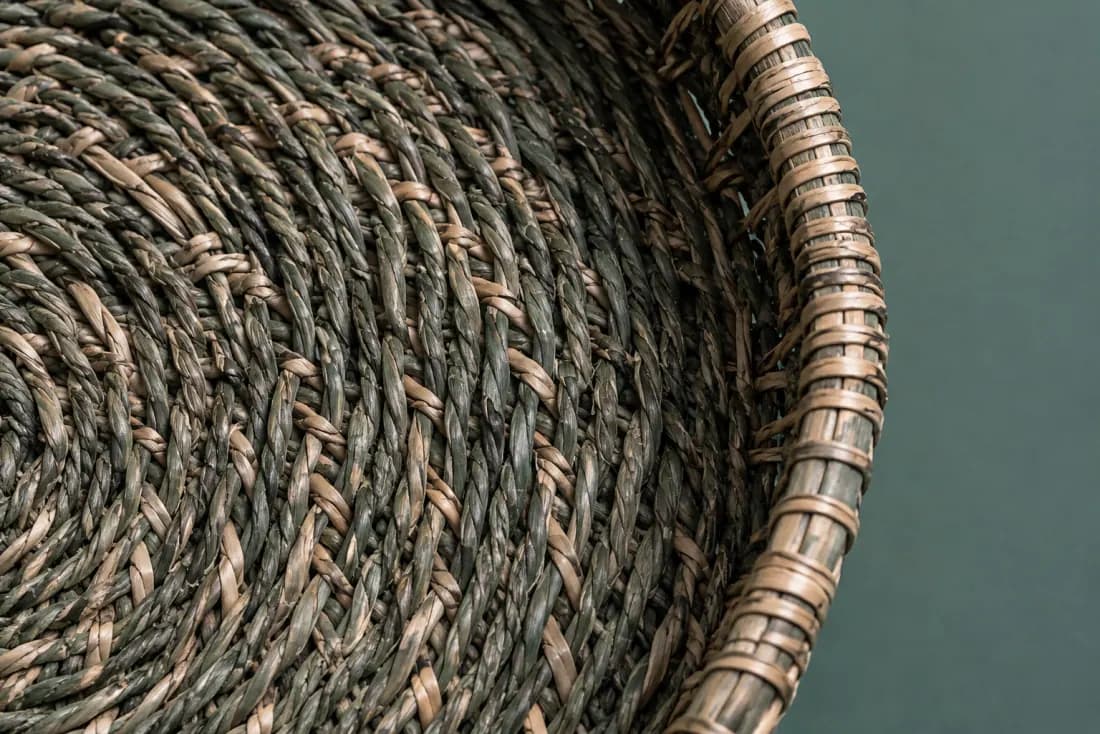 The weave and rim of ON-A-07 in close-up. Coiled from the base centre outward; the cord tail is bound off under the rim at the front.