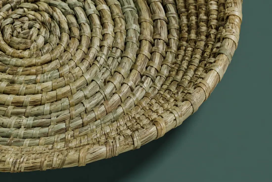 The weave and rim of ON-B-06 in close-up. Coiled from the centre in the opposite hand to its pair; the tail is bound under the rim at the back.