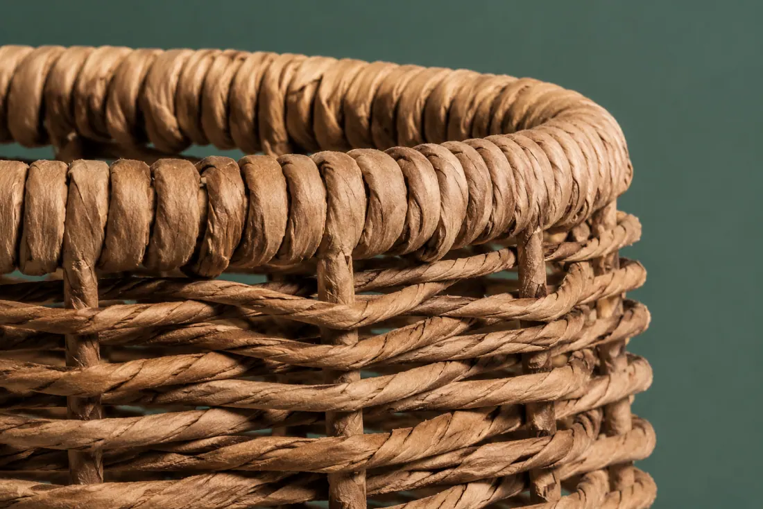 The weave and rim of ON-C-08 in close-up. Twined over vertical paper-cord stakes; the weave closes at the back and stake ends fold over the top ring.