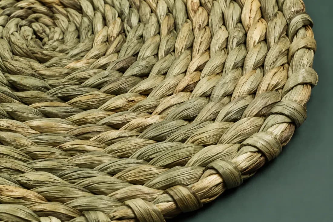 The weave and rim of ON-F-03 in close-up. Twisted rush coiled from the centre; the tail runs out over the last 40 mm of the outer round.