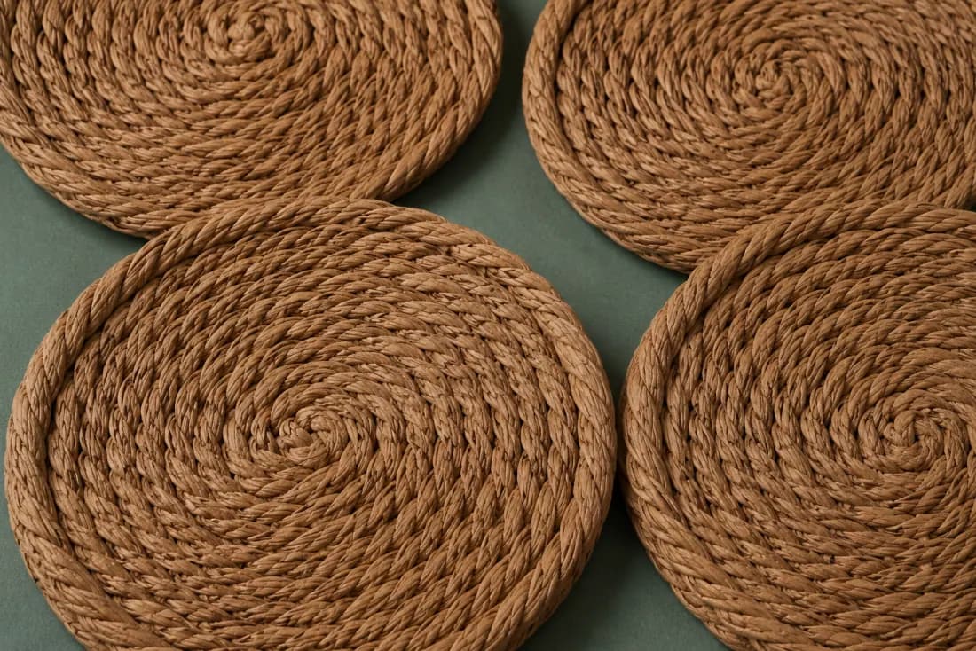 The weave and rim of ON-F-12 in close-up. Each coaster coiled from its own centre; tails are folded under and glued-free tucked.