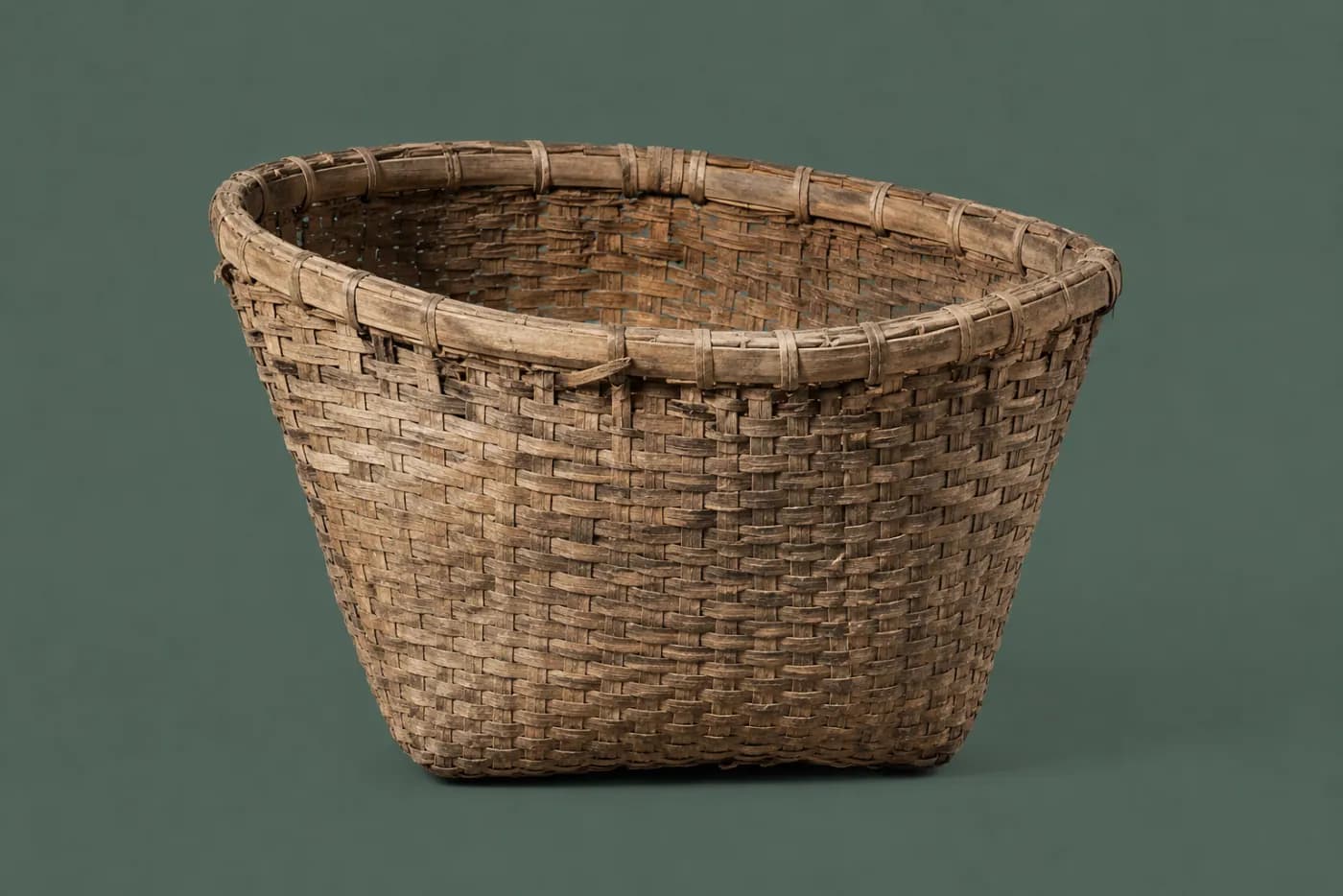 A woven basket carried loaded for a long time, the rim visibly pulled out of round and one wall dished.